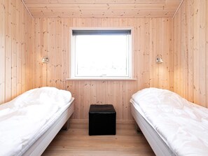 A room with two beds, a window, and a small black ottoman. - 4 Star Holiday Home in Millinge (Millinge)