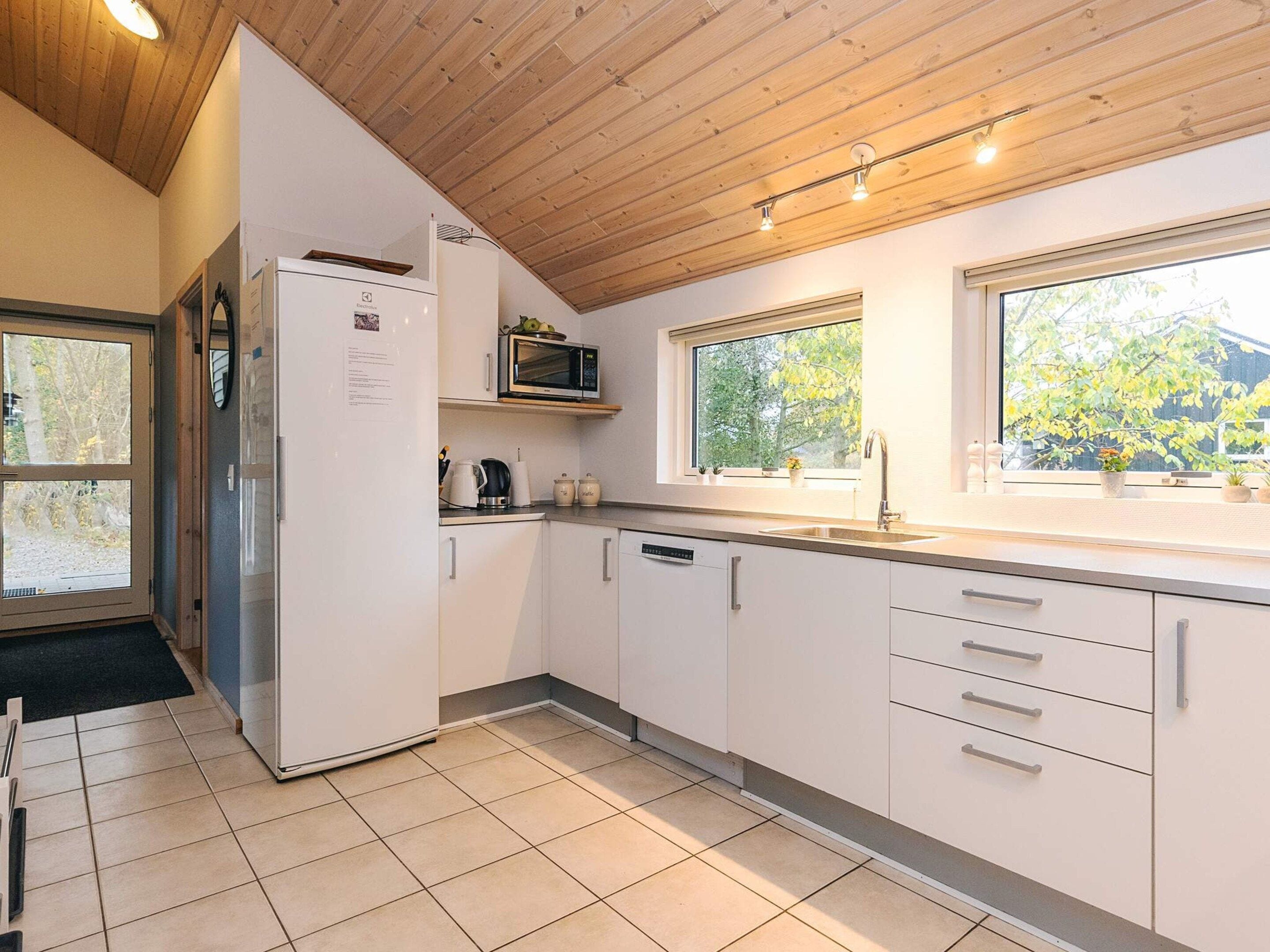 A modern kitchen with white cabinets, a built-in microwave, and a window overlooking greenery.