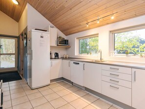 A modern kitchen with white cabinets, a built-in microwave, and a window overlooking greenery. - 4 Star Holiday Home in Millinge (Millinge)