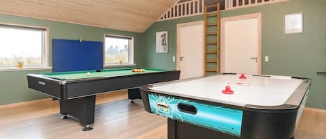 A room with a pool table, a foosball table, a window with a view, and a door.