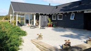 A modern house with a covered patio, outdoor seating, and potted plants. - 4 Star Holiday Home in Millinge (Millinge)