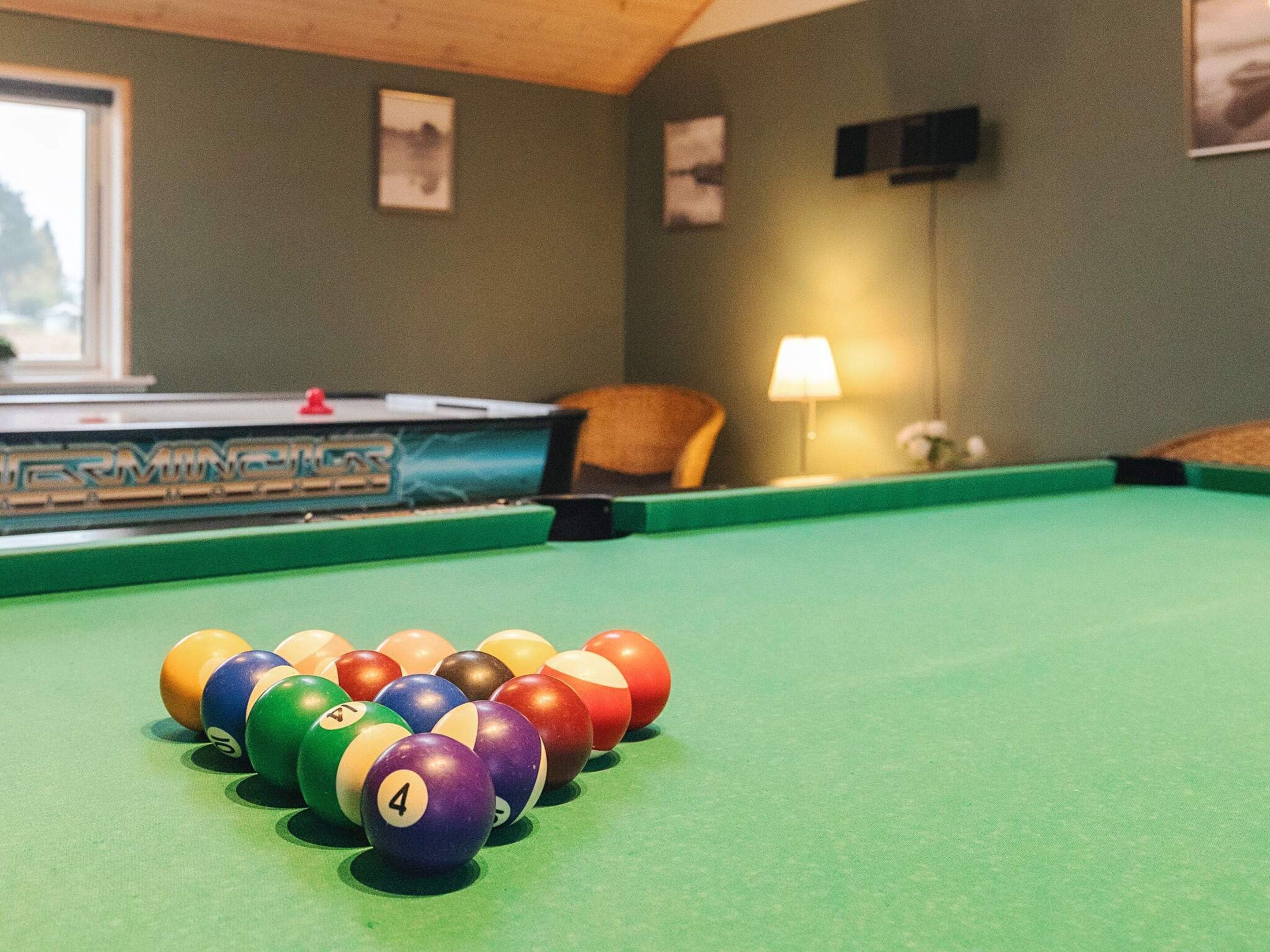 A pool table with balls in the foreground and a billiard table in the background.