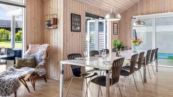A dining area with a wooden interior, a white table, and black chairs.
