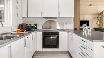 A modern kitchen with white cabinetry, a stainless steel range hood, and a built-in oven.