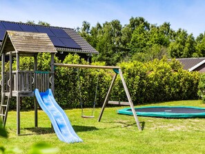 A wooden play structure with a slide and swings, a trampoline, and solar panels on a roof. - 5 Star Holiday Home in Tisvildeleje (Tisvildeleje)