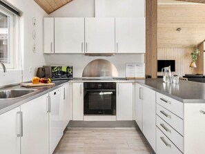 A modern kitchen with white cabinets, stainless steel appliances, and a wooden ceiling. - 5 Star Holiday Home in Tisvildeleje (Tisvildeleje)