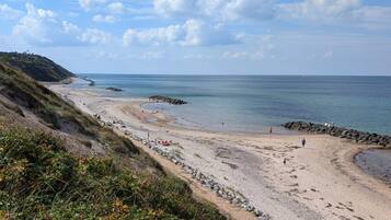 A coastal beach with rocky terrain and a clear sky.