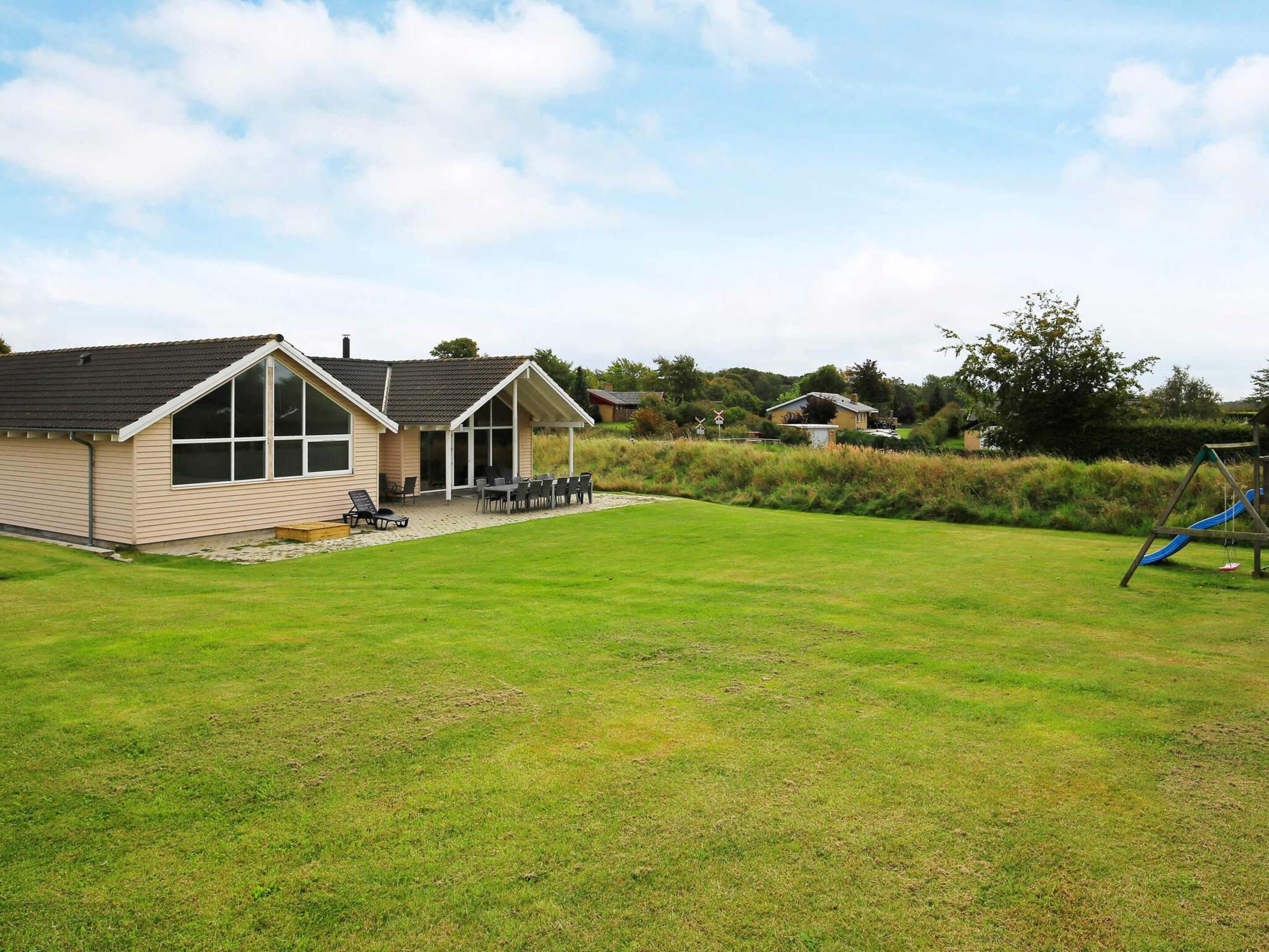 A residential property with a large lawn, a patio with outdoor furniture, and a play area with a slide.