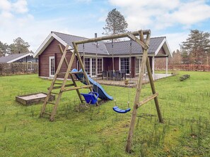 A wooden swing set in a grassy yard with a house in the background. - 5 Star Holiday Home in Hadsund (Hadsund)
