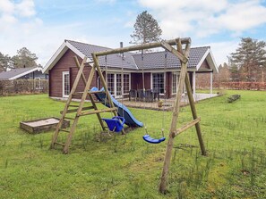 A wooden swing set in a backyard with a house in the background.