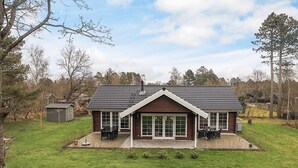 Et toetagers hus med en overdækket terrasse, en hegnet have og et lille skur.