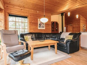 Un interior acogedor de cabaña con un sofá de cuero, una mesa de madera y una silla.