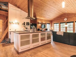 A spacious kitchen with a central island, wooden ceiling, and large windows. - 5 Star Holiday Home in Hadsund (Hadsund)