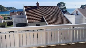 A coastal residential area with terracotta-tiled roofs, white railings, and a wooden deck. - 8 Person Holiday Home in Lindesnes-by Traum (Lindesnes)