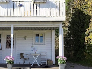 A white wooden house with a porch, a table, two chairs, and potted plants. - 8 Person Holiday Home in Lindesnes-by Traum (Lindesnes)