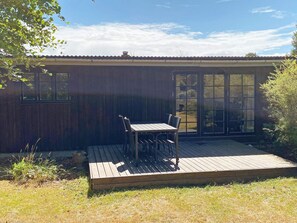 A wooden deck with a table and chairs, a window, and a door.