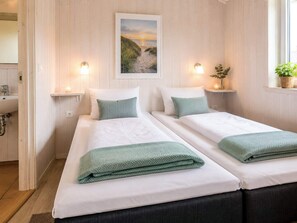 A hotel room with two beds, a window with a view of a beach, and a painting on the wall. - Holiday Home in GrÃ¶mmitz (Groemitz)