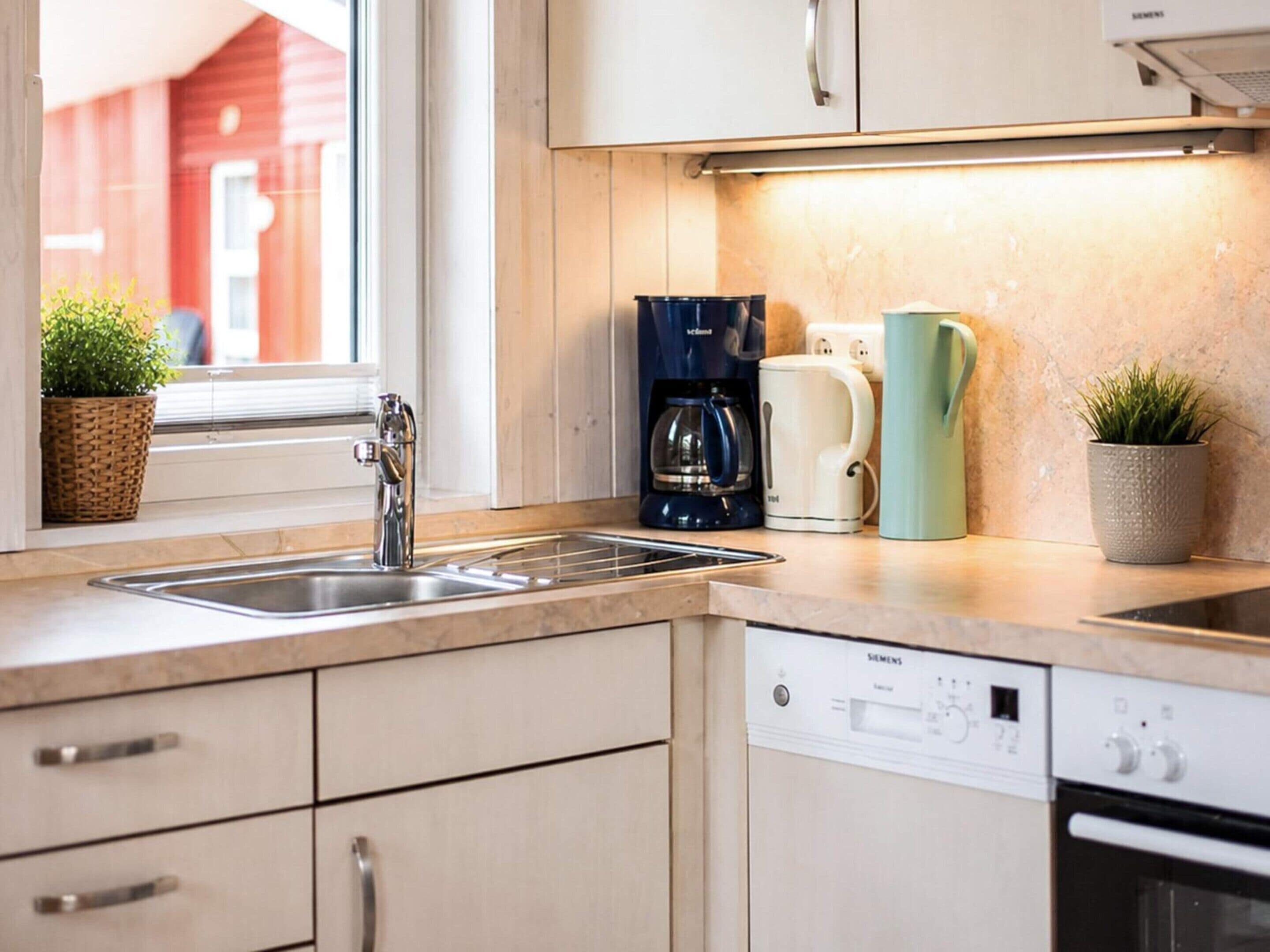 A modern kitchen with a sink, coffee maker, and dishwasher.