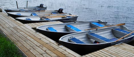 A row of small boats docked on a wooden pier by a calm lake.
