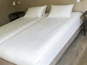 A single bed with white bedding in a room with a wooden floor and a nightstand with a lamp. - 6 Person Holiday Home in Hacksvik (Håcksvik)
