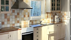 Una cocina con estufa a gas, horno, lavaplatos y ventana con vistas a árboles.