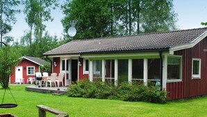 A red building with a covered porch, white-framed windows, and a satellite dish. - 6 Person Holiday Home in Hacksvik (Håcksvik)