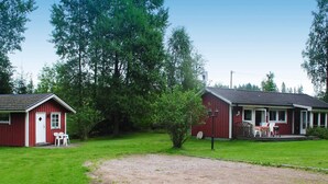 A red building with a porch and outdoor seating, surrounded by greenery. - 6 Person Holiday Home in Hacksvik (Håcksvik)