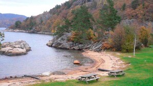 A lakeside view with a picnic area, rocky shoreline, and trees. - 10 Person Holiday Home in Lindesnes (Lindesnes)