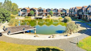 Une rangée de bâtiments modernes à plusieurs étages, dotés de balcons, avec un bassin central et une jetée en bois.
