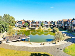 A row of modern, multi-story buildings with balconies, a central pond, and a wooden dock. - 4 Star Holiday Home in Bogense (Bogense)