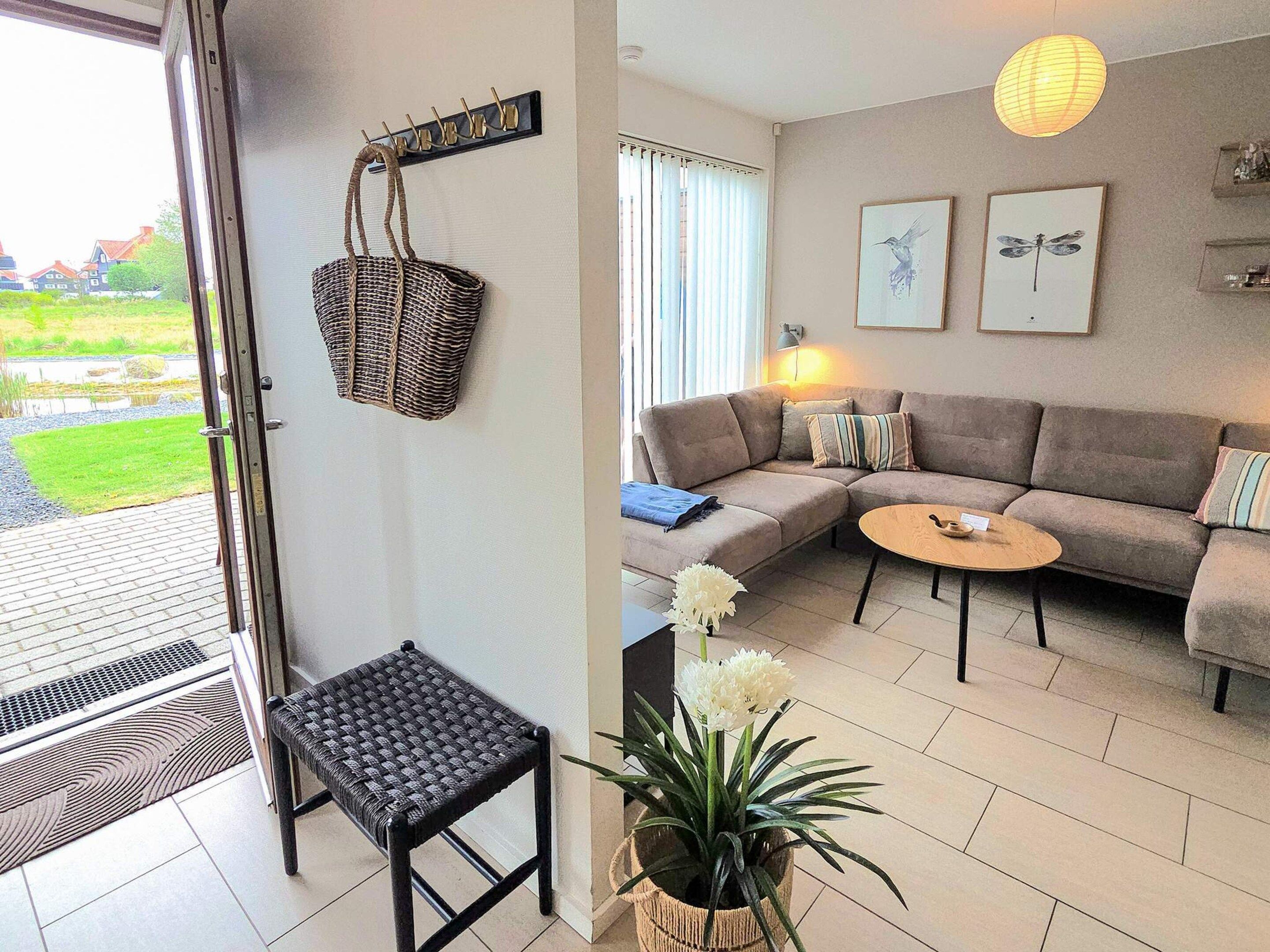 En stue med sofa, et lille bord, en fletkurv, en bænk og en potteplante.