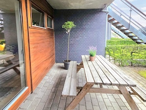 A wooden bench and a table outside a building with a brick wall and a staircase. - 4 Star Holiday Home in Bogense (Bogense)