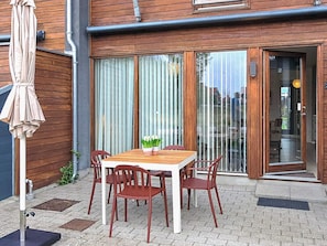 A wooden patio with a table and chairs, a sliding glass door, and a covered umbrella. - 4 Star Holiday Home in Bogense (Bogense)