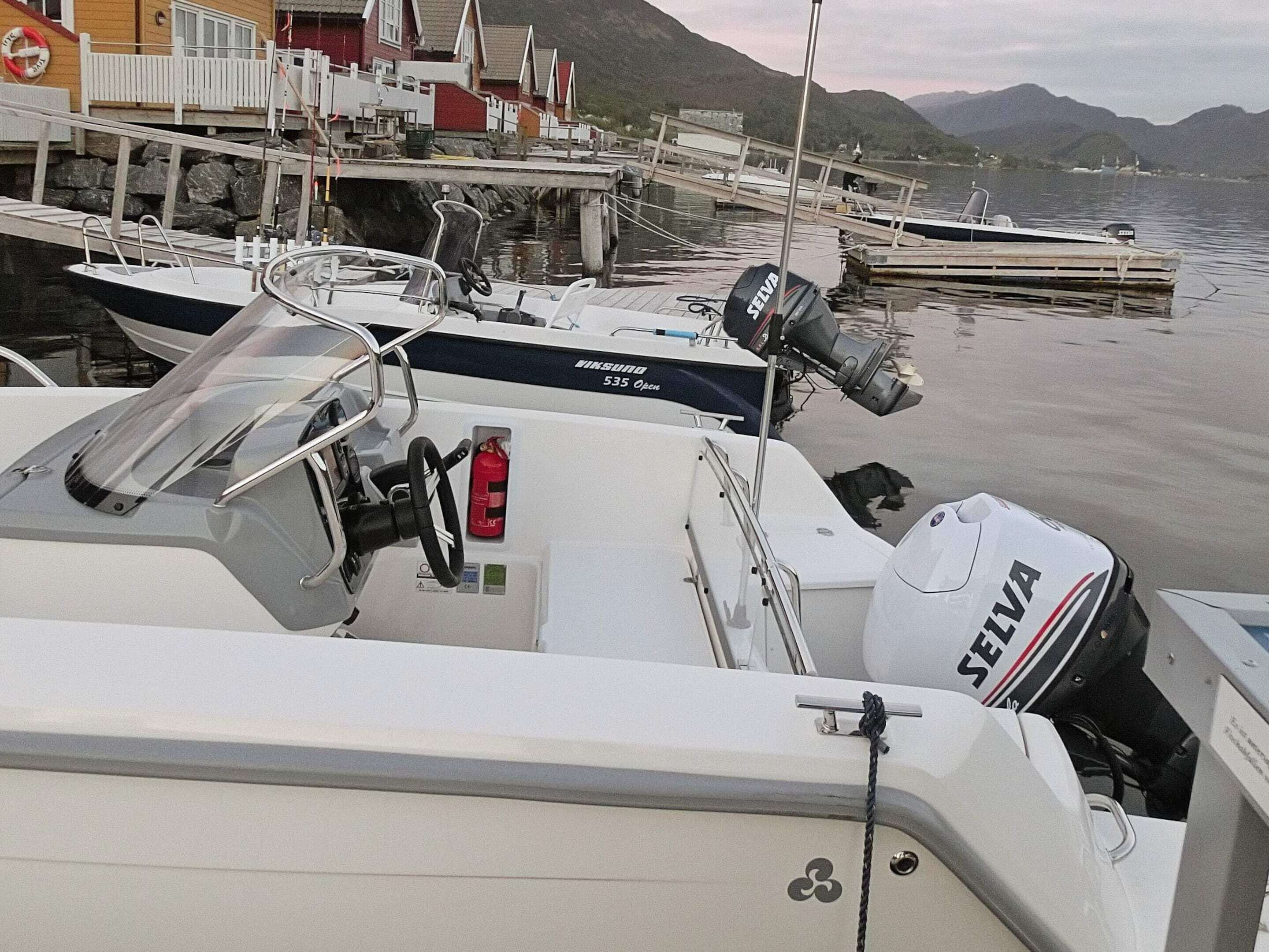 A boat docked at a marina with a cabin, a steering wheel, and a motor labeled 'SEIVA.'