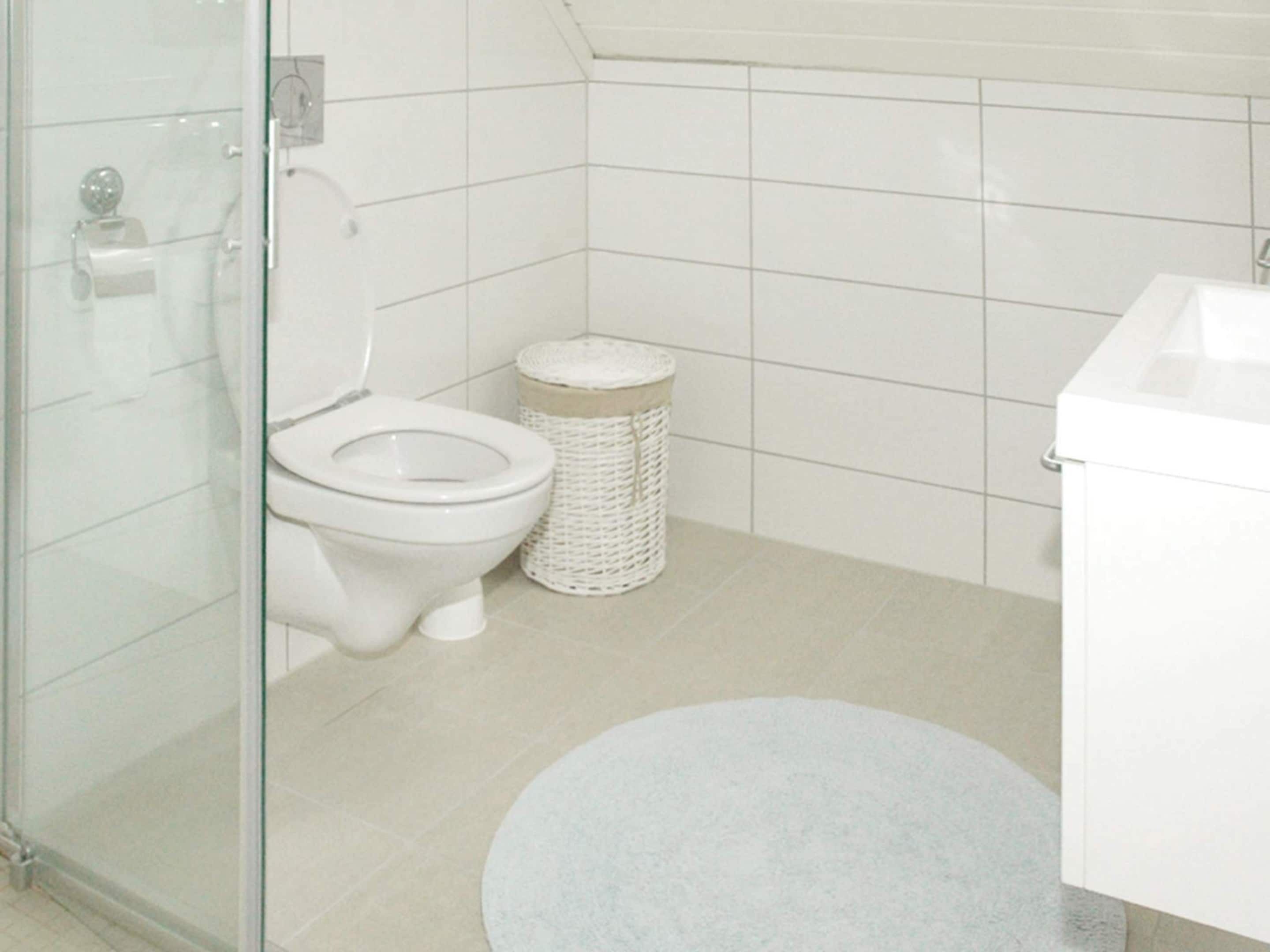 Une salle de bain avec des toilettes, une poubelle et un lavabo.