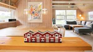 A cozy cabin interior with a dining area, a sofa, and a small model house on the table. - 4 Star Holiday Home in Skagen (Skagen)