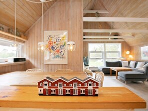 En mysig stuga med en matplats, en soffa och ett litet modellhus som står på bordet.