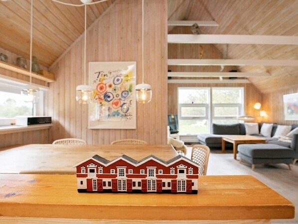 Ein gemütliches Blockhaus-Interieur mit Essbereich, einer Couch und einem kleinen Modellhaus auf dem Tisch.