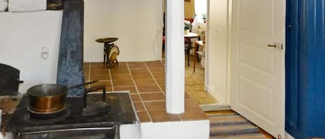 A kitchen with a stove, a sink, and a door leading to another room.