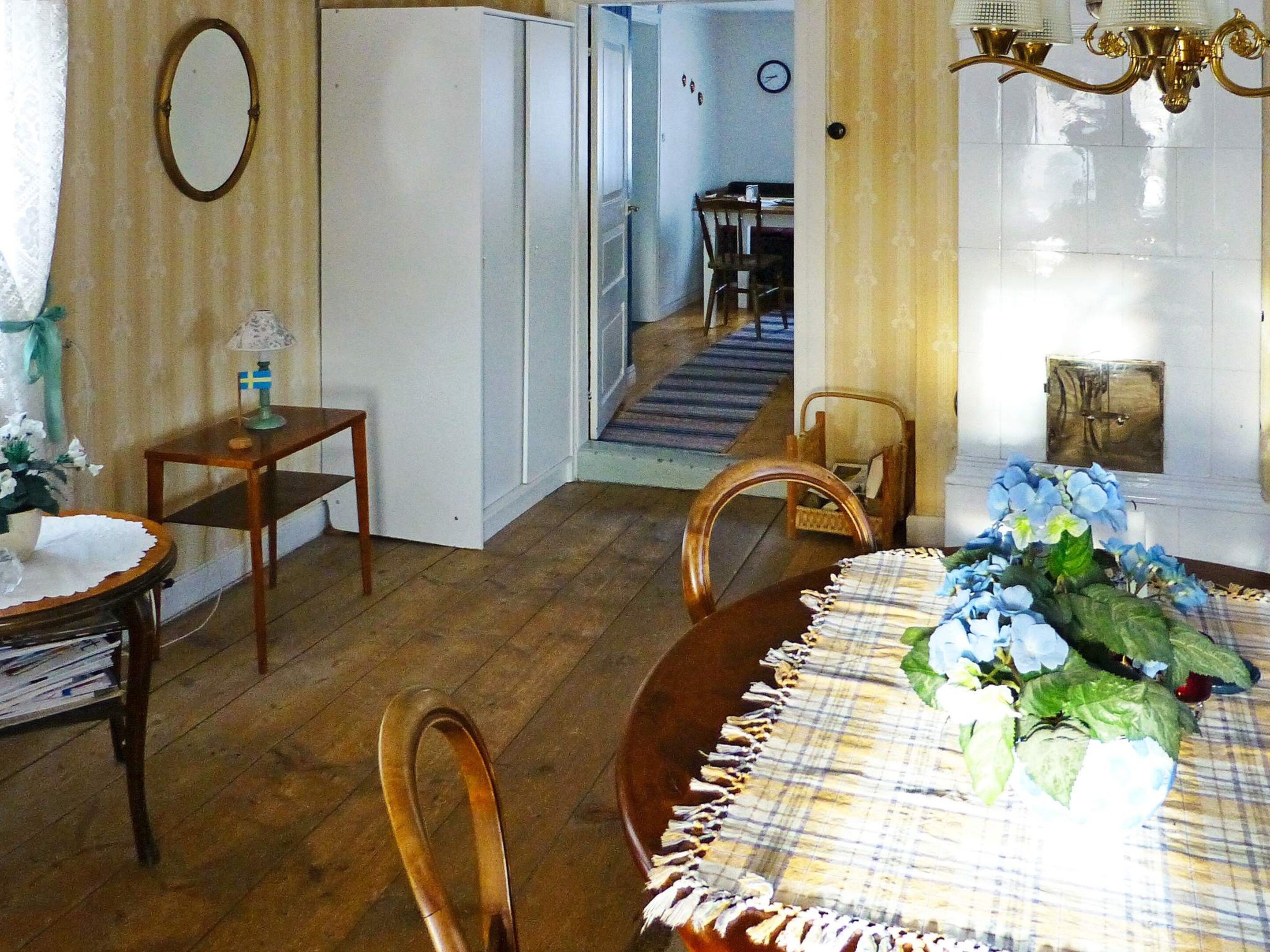 Un comedor con una mesa de madera, sillas, una lámpara de araña y una escalera que lleva a otra habitación.