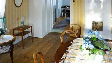 Un comedor con una mesa de madera, sillas, una lámpara de araña y una escalera que lleva a otra habitación.