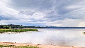 A calm lake with a grassy shore and a cloudy sky.