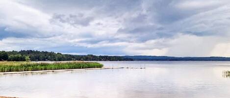 A calm lake with a grassy shore and a cloudy sky.