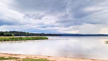 A calm lake with a grassy shore and a cloudy sky.