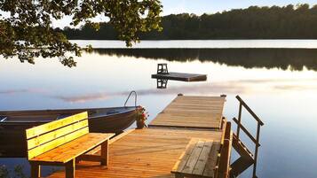 A wooden dock with benches and a small boat, extending into calm water.