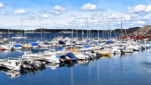 Ein Yachthafen mit zahlreichen angestaubten Booten, ruhigem Meer und einem roten Gebäude im Hintergrund.