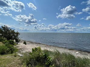 Una playa con cielo despejado y algunas nubes dispersas.