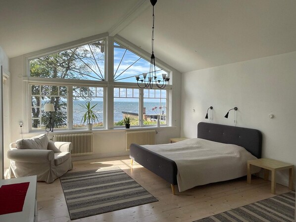 A bedroom with a large bay window, a bed, a chair, a small table, and a radiator. - Holiday Home in Mörbylånga (Morbylanga)