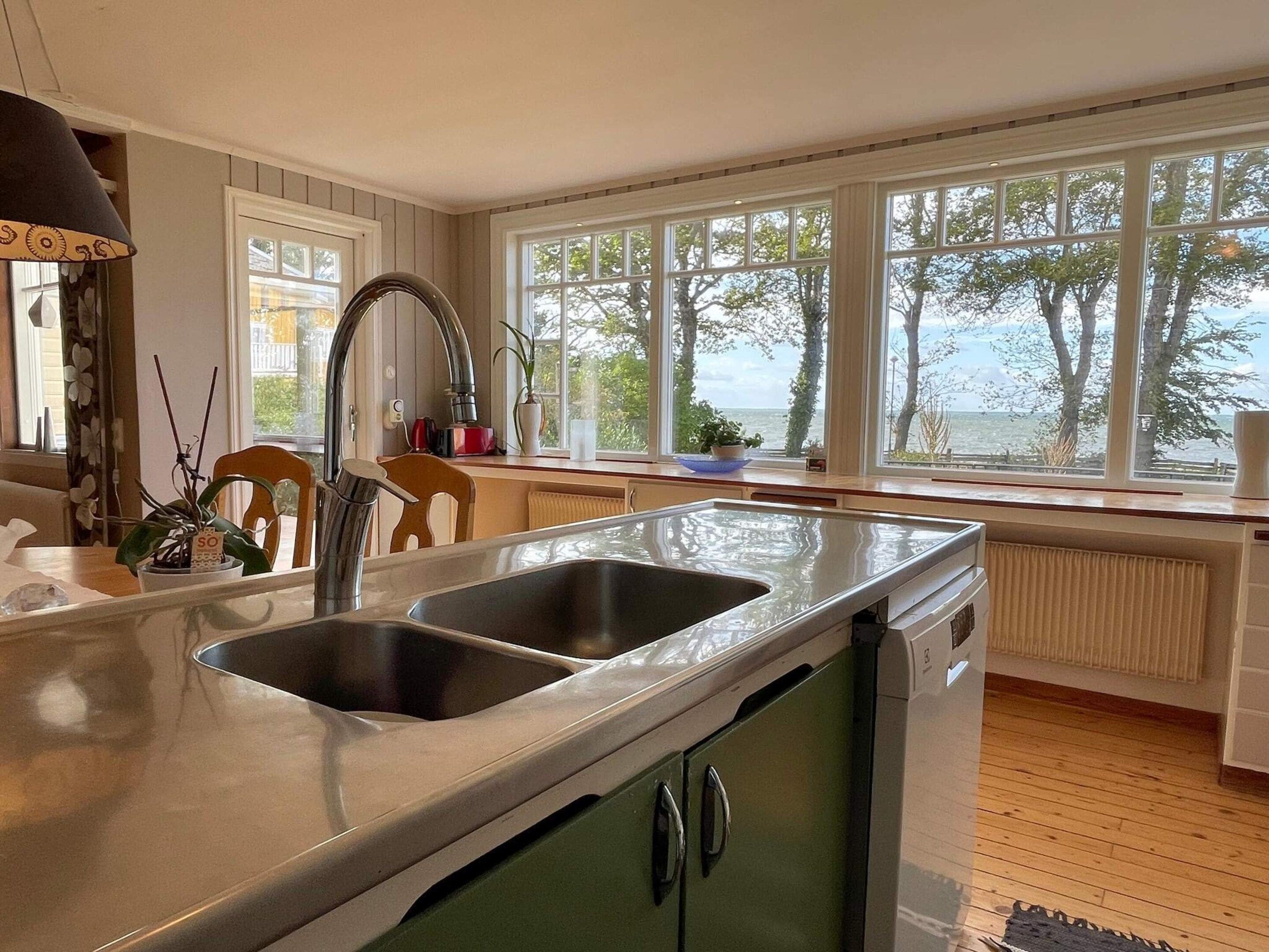 A kitchen with two sinks, a window with a view of trees, and a radiator.