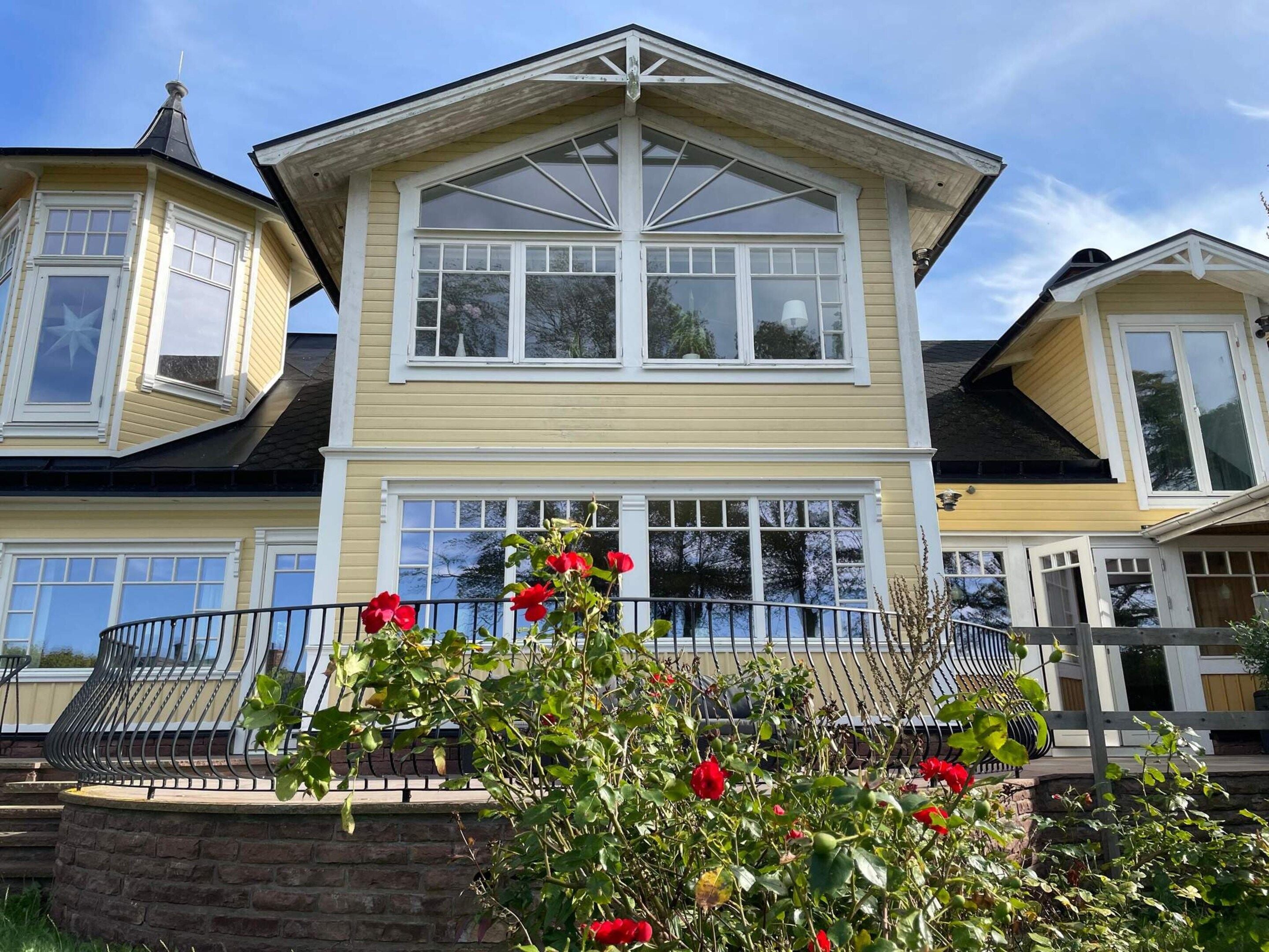 A two-story house with a prominent bay window and a stone staircase leading to the front door.
